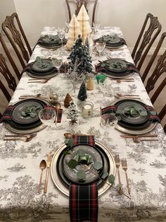 a table set for christmas dinner with place settings