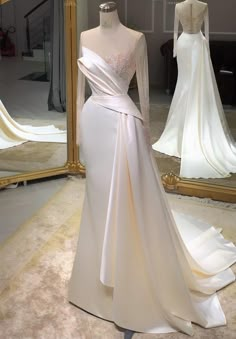 a white wedding dress on display in front of a mirror with other dresses behind it