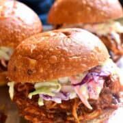 two pulled pork sandwiches with coleslaw and slaw on a silver platter