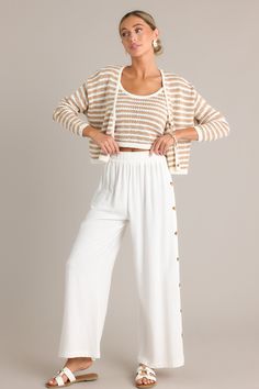 Add a touch of Effortless Glam to your wardrobe with our ivory wide leg pants. Made with high-quality fabric, these pants will elevate any look while providing all-day comfort. Get ready to turn heads with these versatile and stylish pants. These ivory pants feature a high waisted design, an elastic waistband, functional buttons all down the sides, a lightweight material, and a wide leg. 70% Rayon, 30% Linen Unlined Hand Wash Cold Manufactured in China Designed in the USA Model is wearing a size small Ivory Pants, Sorority Rush Dresses, Rush Dresses, Cardigan Crop Top, Cardigan Crop, Stylish Pants, Beach Shop, Dress Bra, Friend Outfits