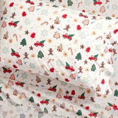 a close up of a bed with christmas themed sheets and pillow cases on top of it