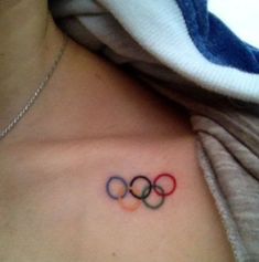 an olympic symbol tattoo on the back of a woman's chest, with three rings in it