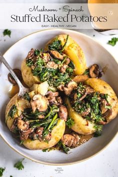 a white bowl filled with potatoes covered in mushrooms and spinach on top of a table