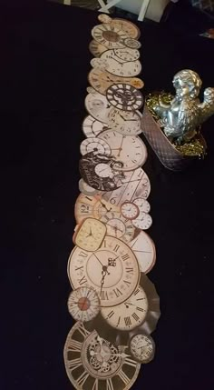 a long row of clocks sitting on top of a black table next to a vase