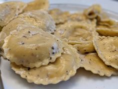 a white plate topped with ravioli covered in gravy next to a fork