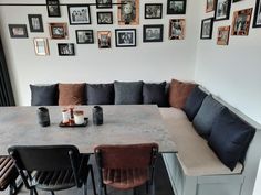 a long table with black and brown chairs in front of pictures on the wall above it