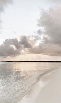 the beach is empty with no people on it and clouds are in the sky above