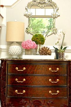 a dresser with flowers and a mirror on top