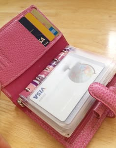 a pink wallet is open on a table with a notepad and pen in it