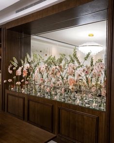 flowers are arranged in glass vases on the wall behind a display case that is filled with water