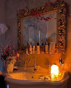 a bathroom sink sitting under a mirror next to a candle and vase with flowers on it