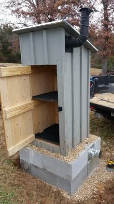 an outhouse built into the side of a field with gravel in front of it