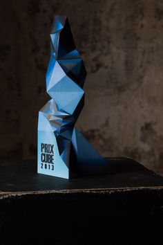 a blue sculpture sitting on top of a wooden table next to a brick wall in the background