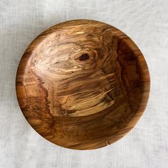 a wooden bowl sitting on top of a white cloth