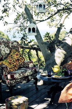 an outdoor area with chairs, table and birdhouse on the tree branch in the background