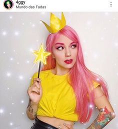 a woman with pink hair holding a wand and wearing a yellow shirt that says mundio da fadaas