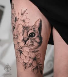 a woman's thigh with a cat and flowers on it