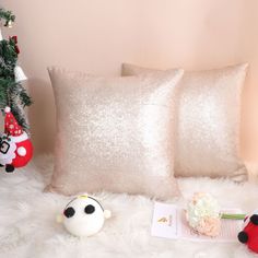 two white pillows sitting next to each other on top of a fur covered floor near a christmas tree