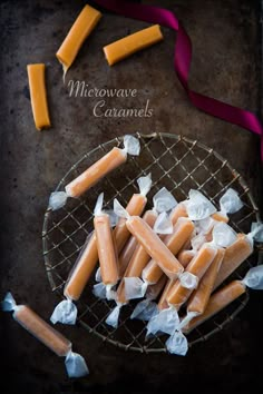 homemade caramel popsicles on a wire rack with wax paper and ribbon around them