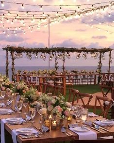 an outdoor dining area with tables and chairs set up for a wedding reception at the beach