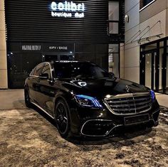 a black car parked in front of a building at night with the word cadillac written on it