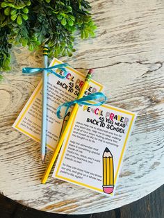 two bookmarks tied to each other on top of a wooden table next to a potted plant