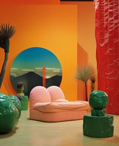 a room filled with different colored furniture and plants in front of an orange wall that has a circular painting on it