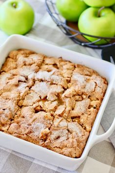 an apple cobbler in a white dish next to green apples