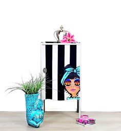 a blue vase sitting next to a black and white cabinet with an image of a woman on it