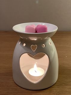 two candles in a heart shaped container on a table