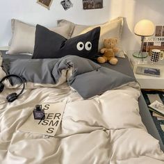 a bed that has some pillows on it and a teddy bear sitting in the corner