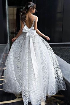 a woman wearing a white dress with a bow on it's back, standing in front of a building