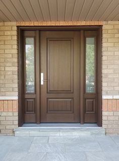 a brown front door with two sidelights and brick pillars on the outside of a house