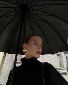 a woman standing under an umbrella in front of a building