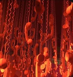 an array of telephones hanging from chains in a room with red lights on the ceiling