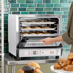 a person pulling out some food from an oven in front of other pastries and breads