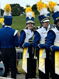 a group of people that are standing in front of some marching band members with their arms around each other