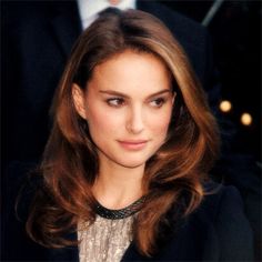 a close up of a person wearing a suit and tie with long hair in front of other people