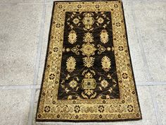 a black and gold rug on the floor in a room with tile floors, white walls and gray tiles