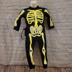 a mannequin wearing a skeleton costume on top of a wooden floor next to a brick wall