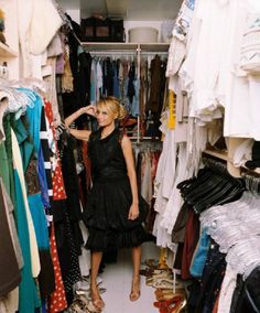 a woman standing in front of a closet full of clothes and shoes, with one hand on her head