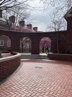 two people are standing in the middle of a brick courtyard surrounded by trees and buildings