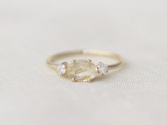 a yellow diamond ring sitting on top of a white cloth covered table with two small diamonds