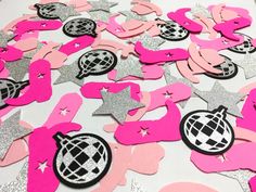 pink and silver confetti cutouts on a white table with glitter stars in the background