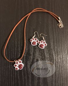 the necklace and earring are made out of wood with red paw prints on it