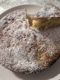 a white plate topped with a cake covered in powdered sugar