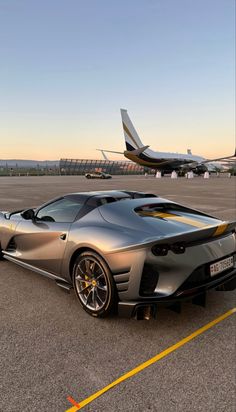 a silver sports car is parked on the tarmac with an airplane in the background