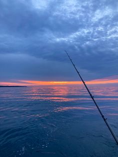 a fishing rod in the water at sunset with clouds and blue sky behind it, as seen from a boat