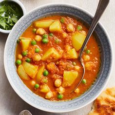 a bowl of stew with peas, potatoes and other foods on the table next to it