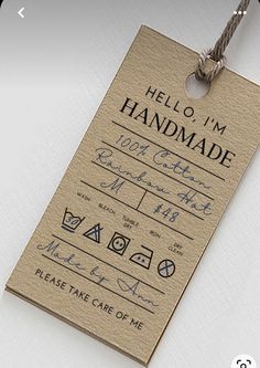 a handmade luggage tag hanging from a string on a white surface with the words hello, i'm handmade written in black ink